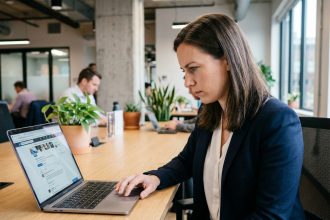 Recruteuse professionnelle analysant des profils de candidats sur les réseaux sociaux depuis son bureau en open space
